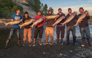 Men on shore holding salmon