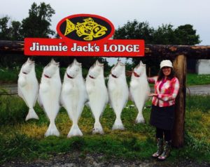 Woman standing next to six hanging halibut