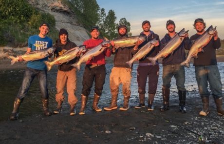 Men on shore holding salmon
