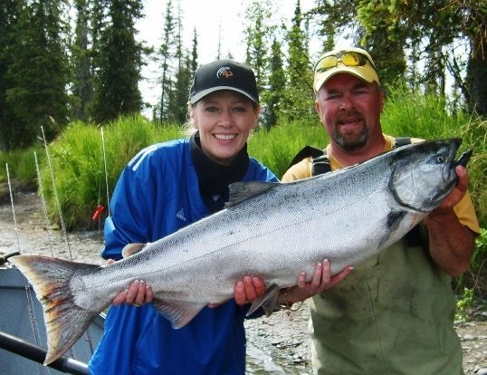 Woman ad guide holding a large salmon