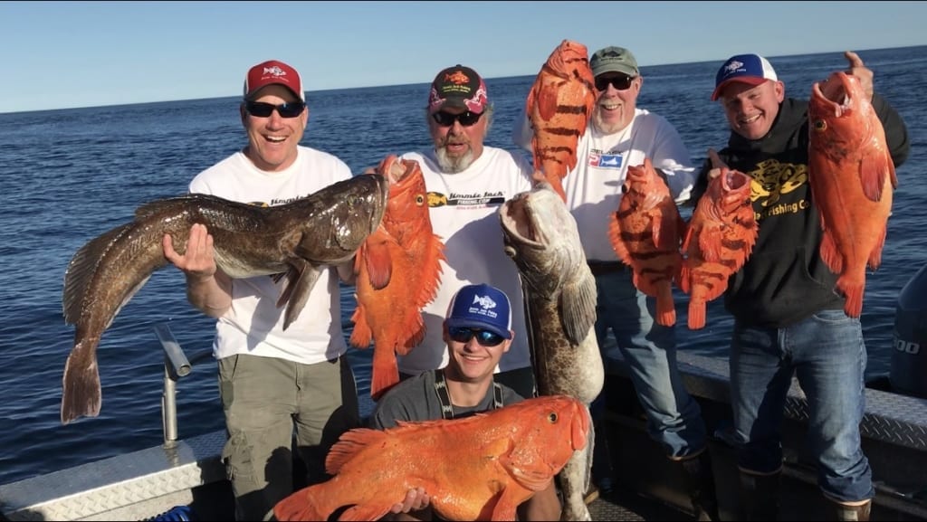 Group of men on fishing boat holding rockfish and groupers
