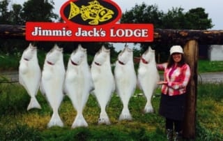 Woman standing next to six rockfish hanging on sign