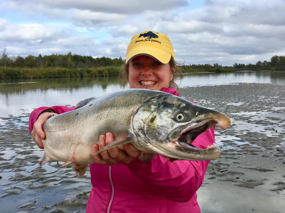 Woman holding a large salmon.