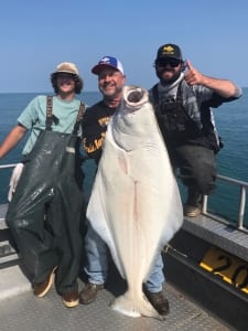 Three fishermen showing off a giant halibut caught near Homer, Alaska.