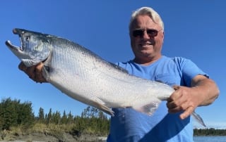 A proud angler hoists up a silver salmon caught while on an Alaskan fishing trip.