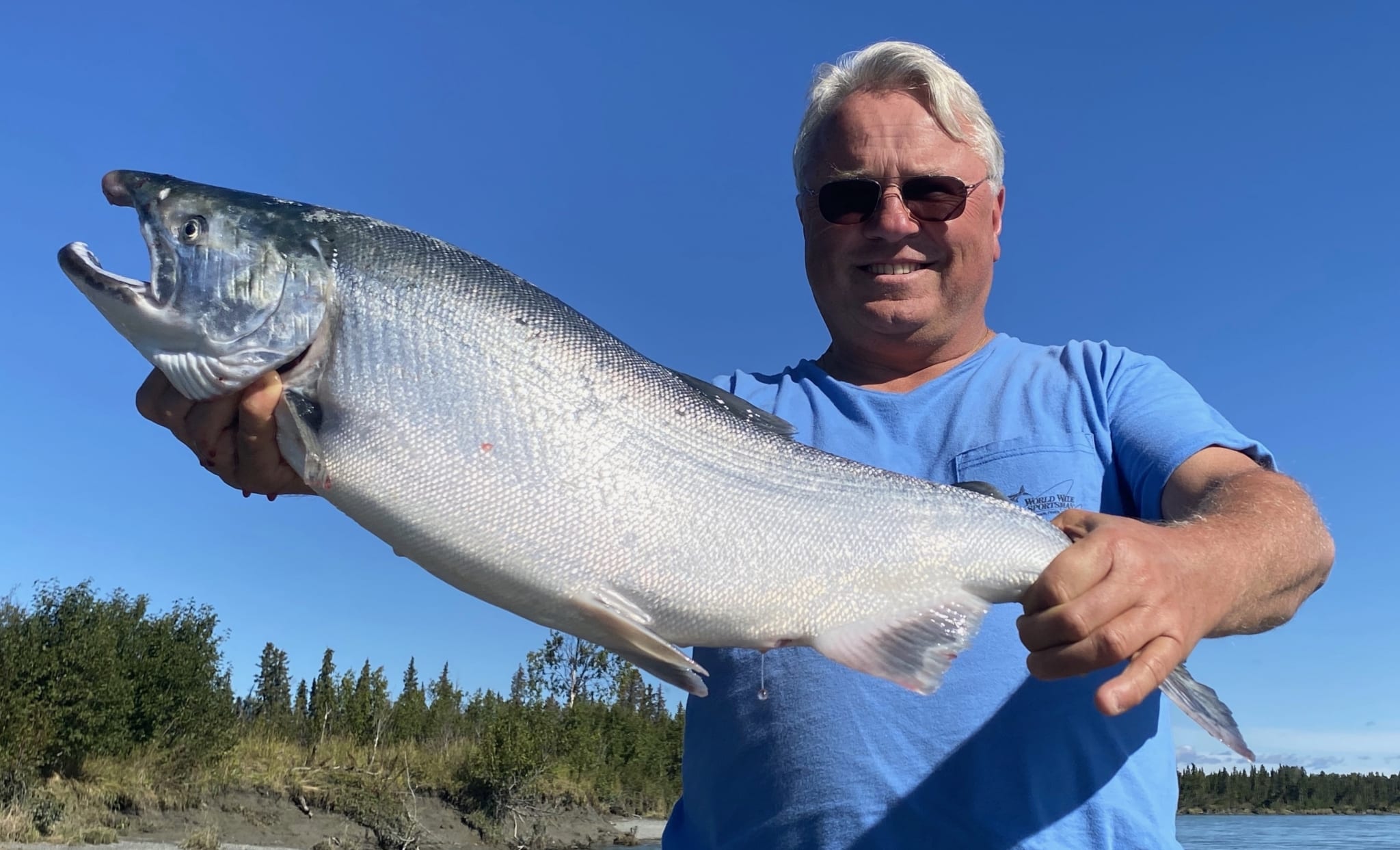 A proud angler hoists up a silver salmon caught while on an Alaskan fishing trip.