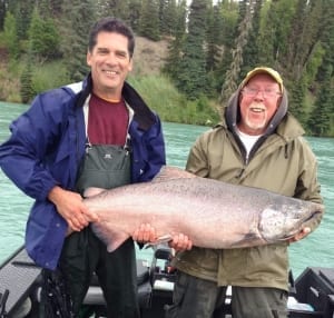 An eager angler smiles while standing next to a devout guide while enjoying a fishing trip.