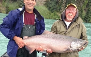 An eager angler smiles while standing next to a devout guide while enjoying a fishing trip.