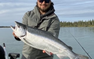 A proud angler displays a large salmon caught while fishing in Alaska.