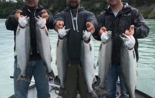 Three men holding two fish each