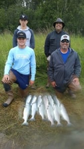 A pair of fathers and sons show off their massive load of salmon.