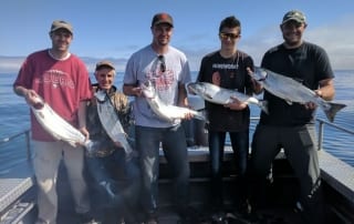 A group of anglers show off their catch during an Alaska fishing vacation.