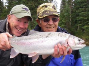 A senior fisherman smiles with Jimmie Jack as they hold an Alaskan salmon.