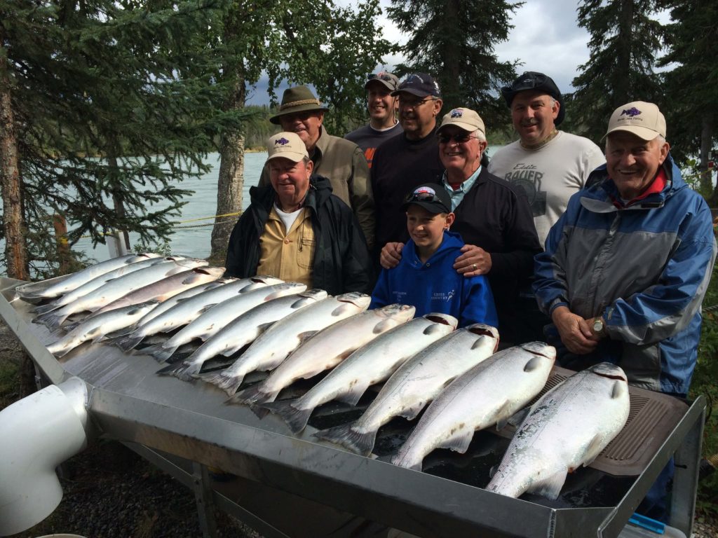 A group of anglers pose in front of their daily salmon haul during an all-inclusive Alaska fishing trip.
