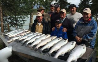 A group of anglers pose in front of their daily salmon haul during an all-inclusive Alaska fishing trip.