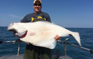 An avid angler holds a massive halibut caught while fishing in Alaska.