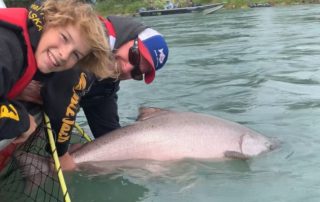 two people holding a salmon in the water.
