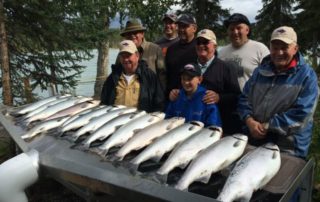 men posing with long table of salmon