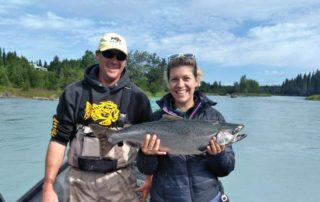 An avid angler poses with her salmon alongside one of Jimmie Jack's seasoned Kenai fishing guides.