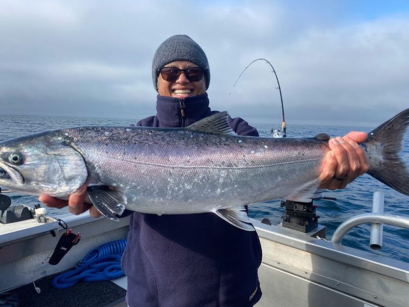 King salmon fishing in Alaska: A avid angler smiles while holding a large king salmon.
