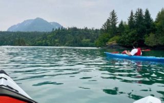 A kayaker enjoys the local waters via kayak during an Alaska sightseeing tour.