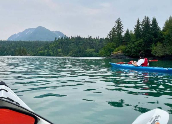 A kayaker enjoys the local waters via kayak during an Alaska sightseeing tour.