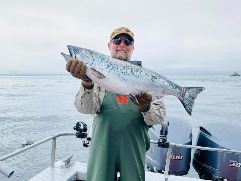 Alaskan Fishing Trip: An avid anglers gleefully hoists a large salmon.