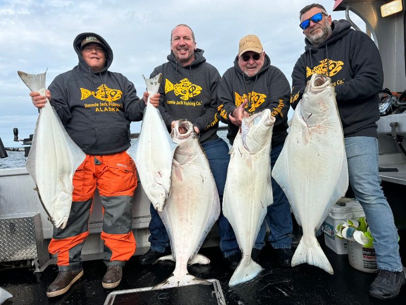 Homer Alaska Fishing: A group of four anglers hold up their massive halibut caught near Homer, Alaska.