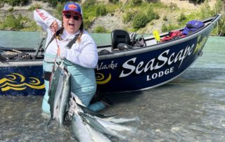 Sockeye Salmon Kenai River: A woman gleefully holds a string of sockeye salmon while standing in the legendary Kenai River.